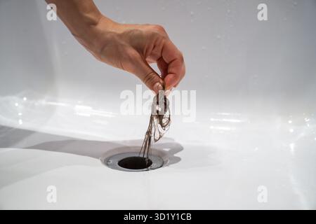 Die Wasserablauföffnung in der Badewanne ist zuhause mit Haarklumpen im Badezimmer verstopft. Stockfoto