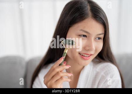 Tägliche Schönheit Routine asiatische Frau Selbstpflege Gua Sha Gesichtsmassage traditionelle Medizin Gua Sha Quarzstein Kosmetik Natur Stockfoto