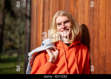 Porträt eines glücklichen europäischen Blonden lächelnd, schauen Sie in die Kamera, entspannen Sie sich im Freien Genießen Sie das sonnige Wetter. Stockfoto