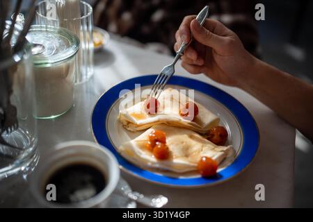 Mann, der leckeres Frühstück in Restaurant-Pfannkuchen mit Marmelade von Äpfeln Rüben. Stockfoto