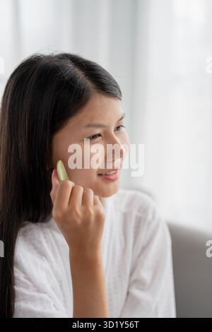 Tägliche Schönheit Routine asiatische Frau Selbstpflege Gua Sha Gesichtsmassage traditionelle Medizin Gua Sha Quarzstein Kosmetik Natur Stockfoto