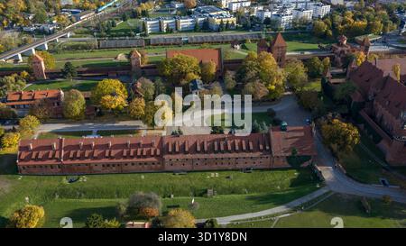 Aus der Vogelperspektive der Burg Malbork in Nordpolen sehen Sie Mauern, Türme und Innenhöfe am Fluss Nogat, mit Herbstbäumen und Stockfoto