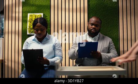 afroamerikanische Bewerber füllen Anmeldeformulare für Bewerbungsgespräche und offene Stellen aus, um eine erfolgreiche Rekrutierung und ein Treffen mit der Personalabteilung zu gewährleisten. Qualifikationen notieren. Kamera A.. Stockfoto