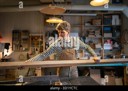 Man Zimmermann Holzelemente in der Werkstatt für die Verarbeitung auf der Tischsäge bereit stellen. Aufmerksamkeit am Arbeitsplatz Stockfoto