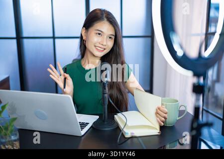 Glückliche junge Frau macht Audio-Podcast im Studio asian Woman, die Podcast auf Tablet mit Kopfhörern und Mikroskop für ON aufnimmt Stockfoto