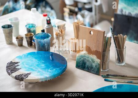 Kunstharzkunstwerke auf Kunstharztisch mit Pinseln, Mischbechern, Holzgestell für Kunsthandwerk Stockfoto