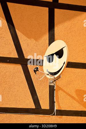 Satellitenschüssel mit Smiley an einer Hauswand in Langenstein, Sachsen-Anhalt, Deutschland, Europa Stockfoto