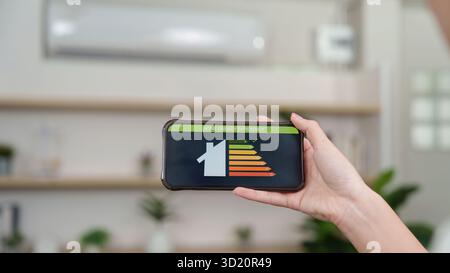 Energieeffizienz Zu Hause. Eine Person, die die Energieeffizienz mit der Smartphone-App überprüft. Stockfoto
