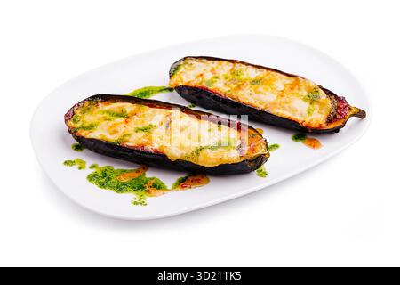 Herzhafte gefüllte Auberginen mit Käse und grüner Sauce auf einem weißen Teller serviert Stockfoto