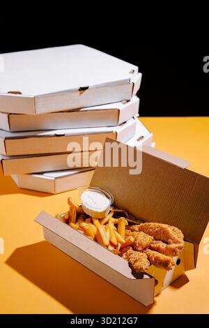 Köstliches frittiertes Hühnchen und Pommes Frites, serviert in Take-out-Behältern vor einem lebhaften Hintergrund Stockfoto