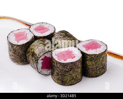 Frische Sushi-Brötchen auf einem langen weißen Teller in minimalistischer Atmosphäre mit lebhaften Farben und moderner Ästhetik Stockfoto