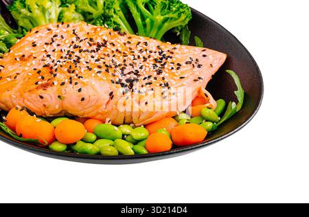 Köstlicher gegrillter Lachs mit Gemüse auf einem schwarzen Teller in stilvoller Atmosphäre Stockfoto