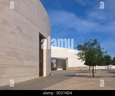 Große, geschwungene Wand des modernen Centro Cultural de Belém mit Bäumen unter blauem Himmel Stockfoto