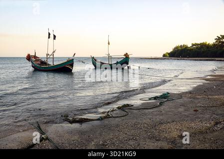 Fischerboote ankern an einem friedlichen Strand bei Sonnenuntergang Stockfoto