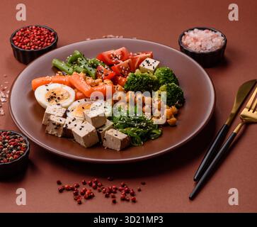 Veganer Salat, Schüsseln mit Kichererbsen, Brokkoli, Tomaten, Tofu-Käse und gekochten Eiern Stockfoto