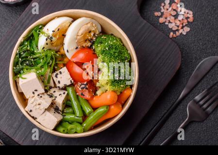 Veganer Salat, Schüsseln mit Kichererbsen, Brokkoli, Tomaten, Tofu-Käse und gekochten Eiern Stockfoto