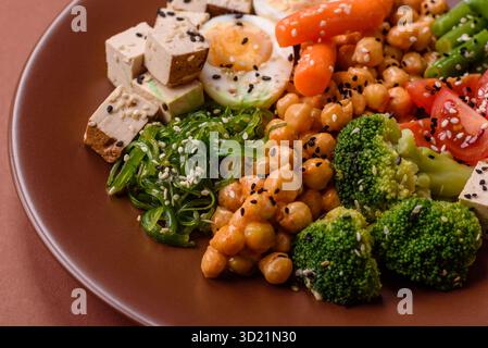 Veganer Salat, Schüsseln mit Kichererbsen, Brokkoli, Tomaten, Tofu-Käse und gekochten Eiern Stockfoto