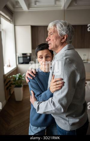 Ehefrau tröstet besorgten Ehemann. Ältere verängstigte Paare, die sich gegenseitig mit Liebe unterstützen Stockfoto