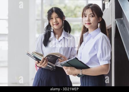 Portrait kluge Schülerinnen in Uniform, die auf dem modernen Schulcampus nebenan stehen. Thai Highschool Schülerin schaut weg. Stockfoto