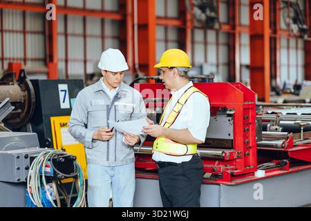 Professionelle Ausbildung leitender Ingenieure, zwei Arbeiter arbeiten, Techniker Supervisor Mann arbeiten mit jungen Ingenieur in der Stahlindustrie Herstellung fac Stockfoto