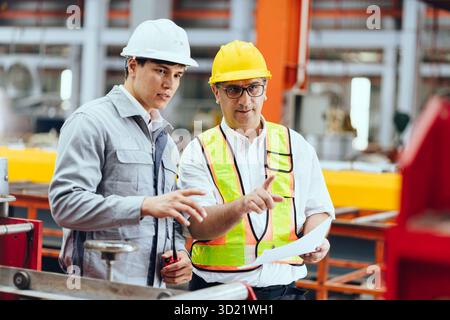 Professionelle Ausbildung leitender Ingenieure, zwei Arbeiter arbeiten, Techniker Supervisor Mann arbeiten mit jungen Ingenieur in der Stahlindustrie Herstellung fac Stockfoto