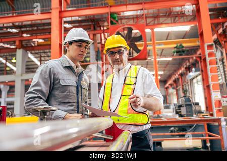 Professionelle Ausbildung leitender Ingenieure, zwei Arbeiter arbeiten, Techniker Supervisor Mann arbeiten mit jungen Ingenieur in der Stahlindustrie Herstellung fac Stockfoto