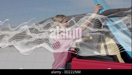 Eine Frau mit rosa Hemd, die blaue Röhre in den roten Kofferraum in der Parkbucht steckt Stockfoto
