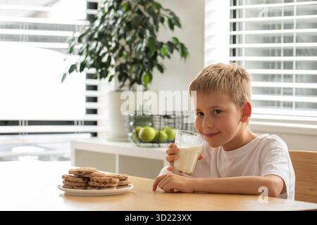 Ein lächelnder Junge mit frischer Bauernmilch und selbstgemachten Keksen. Frühstück, Milchprodukte Stockfoto
