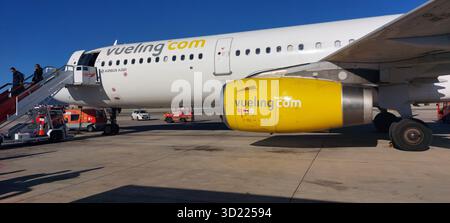 Fluggäste, die in ein weißes Regionalflugzeug auf dem Flughafenparkplatz einsteigen, bereiten sich auf den Abflug unter klarem blauem Himmel vor Stockfoto