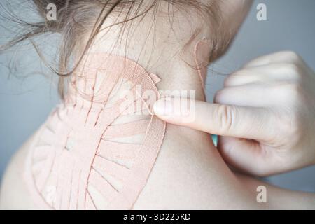 Weibliche Anwendung von therapeutischem Kinesiologieband am Hals zur Schmerzlinderung und Muskulatur Stockfoto