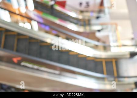 Verschwommener Blick auf Rolltreppen im Einkaufszentrum mit bunten Lichtern und Reflexionen Stockfoto