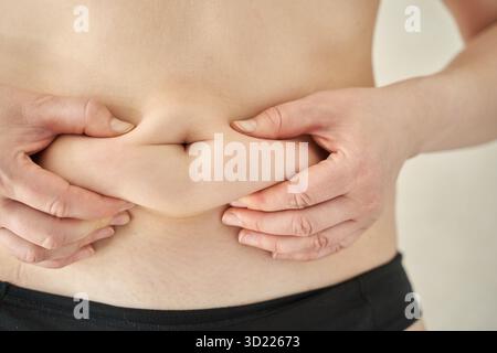 Nahaufnahme der Hände, die Haut auf männlichen Bauch drücken, Körperfett für die Gesundheit Stockfoto