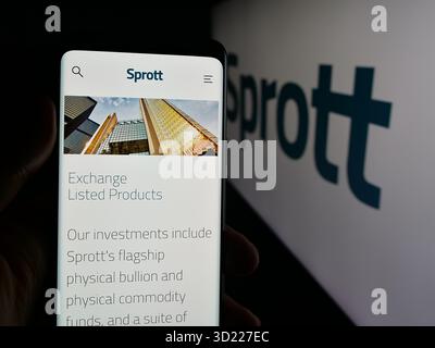 In dieser Abbildung hält eine Person ein Handy mit der Webseite der kanadischen Metallinvestmentgesellschaft Sprott Inc. Vor dem Logo. Stockfoto