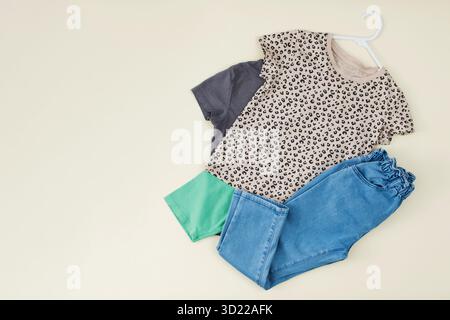 Ein Set stilvoller Kleidung für Kinder. Jeans und ein T-Shirt auf beigefarbenem Hintergrund für ein Mädchen. Stockfoto