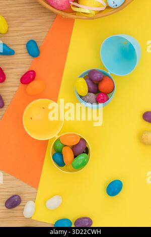 Heller Hintergrund mit Süßigkeiten in Form von Ostereiern in Plastikeiern. Das Konzept der Eierjagd. Frohe Ostern. Draufsicht. Stockfoto