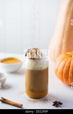 Streuen Sie Zimt auf einen leckeren Kürbislatte mit Schlagsahne. Stockfoto