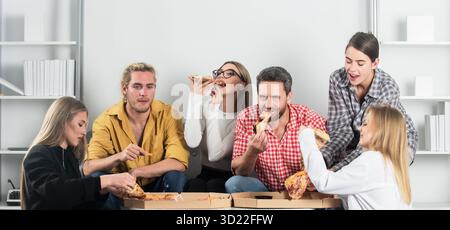Eine Gruppe von Freunden genießt Pizza zu Hause. Abendessen am Wochenende mit Freunden. Glückliche Freunde, die sich über geteilte Stücke Pizza zusammensetzen. Freunde in entspannter Atmosphäre Stockfoto