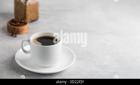 Schwarzer Instant-Kaffee in einem weißen Becher auf grauem Hintergrund. Speicherplatz kopieren. Stockfoto
