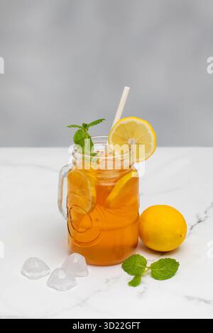 Ein Glas mit einem sommerlichen kühlen Getränk. Eistee mit Zitrone und Minze. Stockfoto