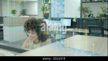 Tippen einer Frau im Blazer mit Computer und Tastatur am Schreibtisch, mit Pflanzen, Binärcode-Overlay Stockfoto