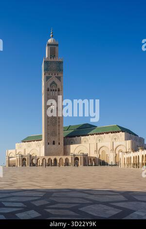 Die Hassan II Moschee steht unter einem klaren blauen Himmel mit ihrer komplexen Architektur und dem hohen Minarett. Casablanca, Marokko Stockfoto