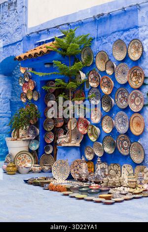 Farbenfrohe Töpferwaren auf der blauen Wand mit lebendigen Mustern und Designs. Chefchaouen, Marokko Stockfoto