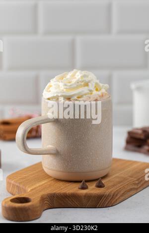Köstlicher Kakaobecher mit Schlagsahne auf Holzbrett Stockfoto