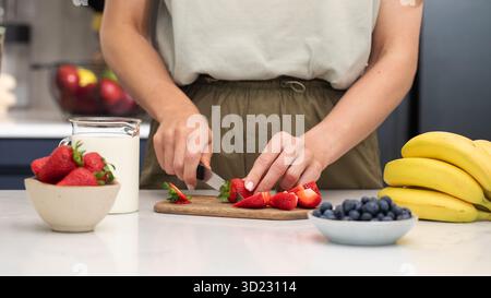 Frau, die Erdbeeren schneidet. Frische Beeren für ein gesundes Frühstück zubereiten Stockfoto