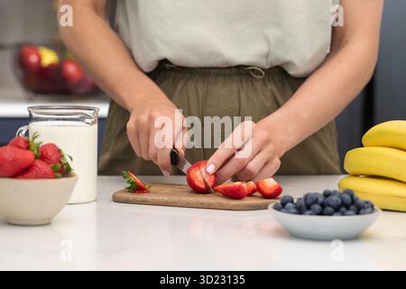 Frau, die Erdbeeren schneidet. Frische Beeren für ein gesundes Frühstück zubereiten Stockfoto
