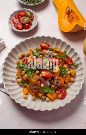 Frischer Kichererbsen- und Kürbissalat mit Tomaten und Kräutern für eine gesunde Ernährung. Herbstsalat Stockfoto