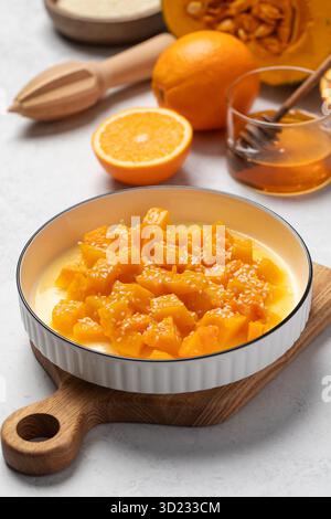 Schüssel mit frisch gewürfeltem Kürbis mit Sesam und Zitrusfrüchten auf Holzbrett Stockfoto