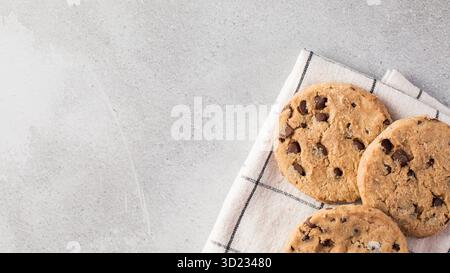 Frisch gebackene Schokoladenkekse auf einem Küchentuch vor einem minimalistischen grauen Hintergrund. Stockfoto