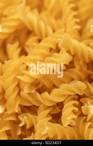Nahaufnahme ungekochter Fusilli-Nudeln mit detaillierter Textur und Spiralformen Stockfoto