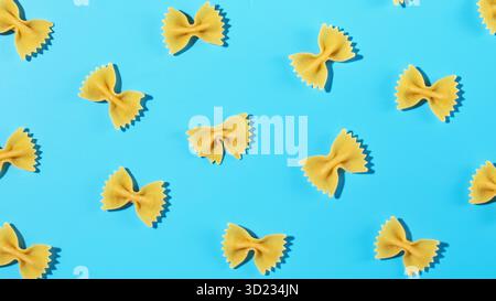 Ungekochte Pasta mit Fliege, farfalle auf blauem Hintergrund in einem dekorativen Muster Stockfoto